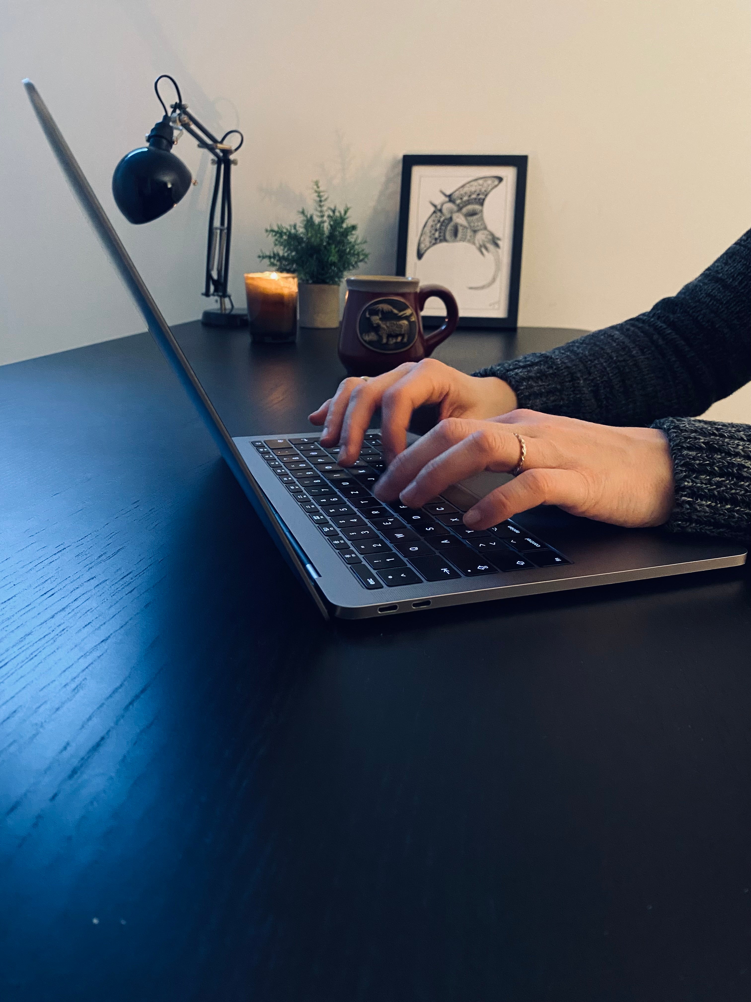 Schreibende Hand neben einem Laptop